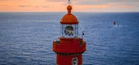 red and white lighthouse on the sea during daytime