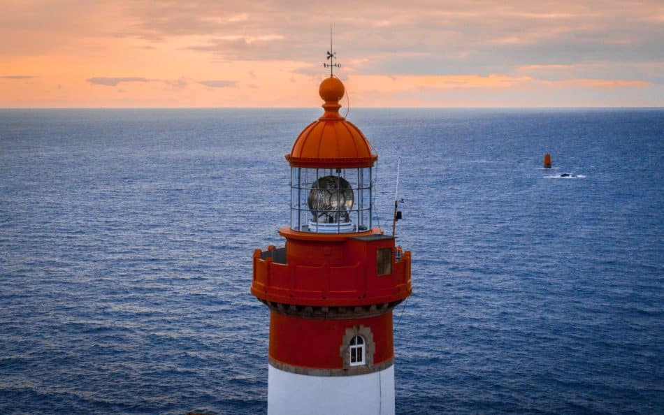 red and white lighthouse on the sea during daytime